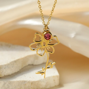 Macro view of gold flower pendant necklace featuring hollow petals and pink zircon stone