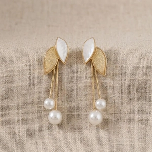Elegant long leaf tassel earrings with pearls and gold plating on textured fabric