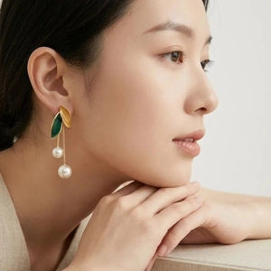Elegant gold leaf tassel earrings with green enamel and white pearls on Asian model
