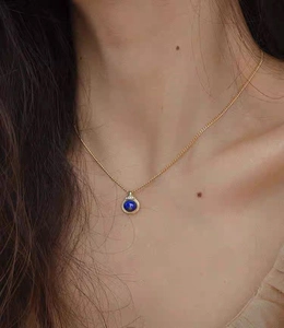 Exquisite gold necklace with a round natural blue lapis lazuli pendant on a female model