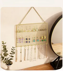 Detail of gold metal jewelry wall organizer with diamond mesh grid and ten storage hooks