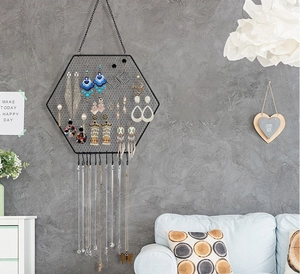 Detail view of hexagonal metal jewelry organizer with grid and 10 necklace hooks on a wall