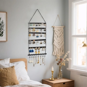 Close-up of wall-mounted black metal jewelry organizer with multi-layer earring slots