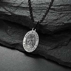 Macro view of Saint Michael oval pendant with engraved protector text on black rock base