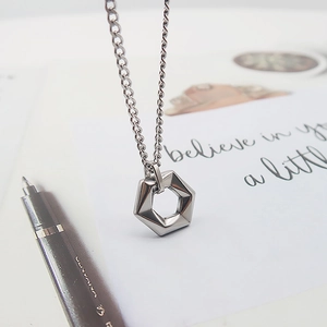 Detailed view of silver hexagonal pendant necklace on white card with sleek chain link