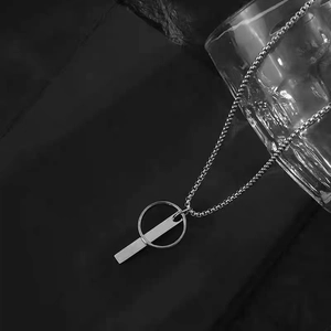 Vue macro d'un collier minimaliste avec pendentif barre et anneau sur roche noire