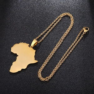 Detail view of a polished gold Africa map pendant necklace on a textured black surface