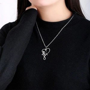 Detailed view of silver heart pendant with custom name engraving on black sweater