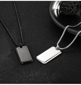 Detail of minimalist black and silver rectangular military dog tag pendants on snake chains