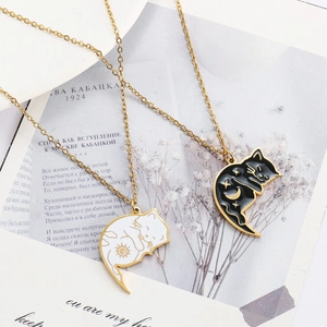 Detail of interlocking sun and moon cat necklaces with enamel inlay on vintage background