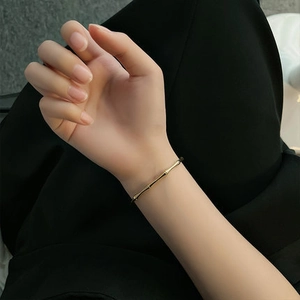 Bracelet jonc minimaliste doré style bambou en acier inoxydable porté par un mannequin