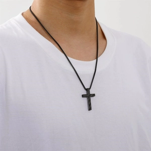 Close-up of black stainless steel cross necklace with engraved inspirational text