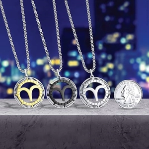 Three Aries zodiac necklaces in gold, black, and silver finishes on stone texture