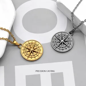 Detalle de colgantes de brújula en acero inoxidable oro y plata sobre fondo de piedra