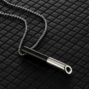 Minimalist bicolor stainless steel breathing whistle necklace on elegant black grid background