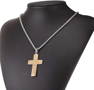 Dettaglio di mani in preghiera e preghiera della serenità su collana con croce bicolore