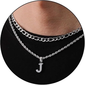 Detail of silver layered necklace with Figaro chain, rope chain, and letter J pendant