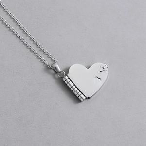 Polished silver heart locket pendant with hinge detail and heart-shaped cutout on thin chain