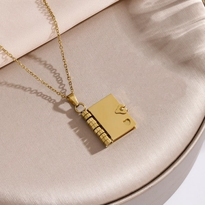 Elegant gold stainless steel book necklace with heart patterns on champagne satin background