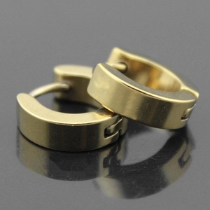Detailed macro view of 4mm wide golden stainless steel huggie earrings on black reflective surface