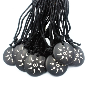 Black round pendant necklace with white sun spiral pattern on woven cord cord