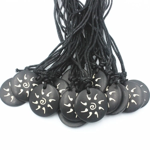 Black round bovine bone pendant necklace with engraved sun pattern on a woven cord