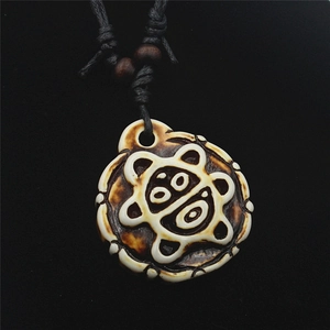 Vista macro di una collana etnica con pendente intagliato cordoncino nero e perline