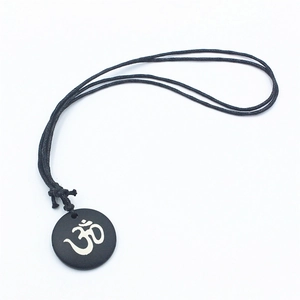Collana minimalista con pendente Om in osso nero e cordino nero regolabile su sfondo bianco