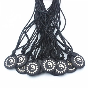 Yin Yang Tai Chi bone pendant necklace with sunburst sun pattern on black cord strap