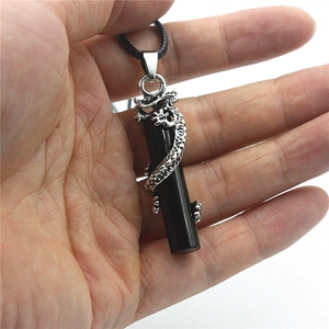 Vue macro d'un dragon argenté sculpté autour d'un pendentif cylindrique noir poli