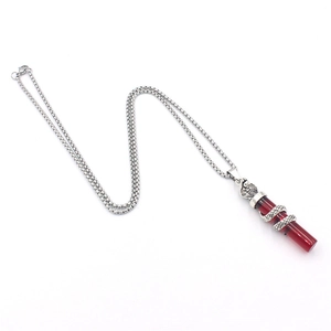 Macro detail of punk cobra snake pendant featuring a red resin cylinder and silver box chain