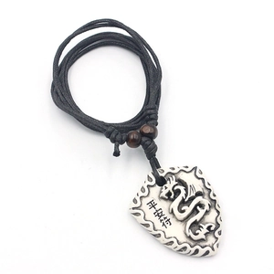 Detailed view of the dragon motif shield pendant with wooden beads on black cord