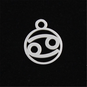 Macro shot of silver Cancer zodiac pendant with hollow design on black velvet