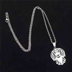 Detail of hollow dog silhouette pendant and fine stainless steel link chain on black surface