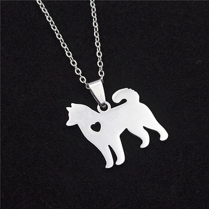 Macro shot of silver stainless steel Shiba Inu dog pendant with a heart cut-out on black sand