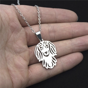 Minimalist stainless steel hollow dog pendant necklace held in hand for scale