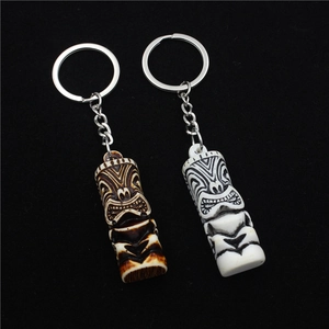 Detail of Tiki totem keychains in faux wood and bone finishes on black velvet background