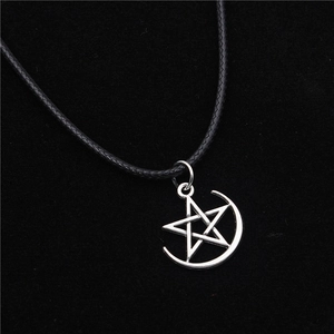 Collana con ciondolo a stella e luna con cordino nero su sfondo di velluto nero