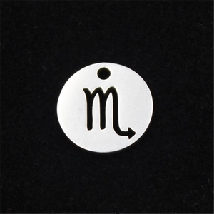 Macro detail of a silver stainless steel round pendant with Scorpio zodiac cutout design