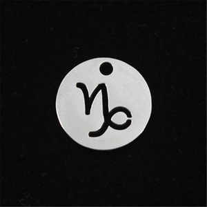 Macro shot of polished stainless steel Capricorn zodiac hollow pendant on black background