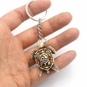 Resin sea turtle keychain with yin yang shell pattern and metal ring on white background