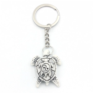 Lucky turtle keychain with yin yang resin shell and silver metal ring on white background
