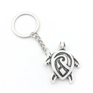 Vintage silver sea turtle keychain with tribal pattern engraving on a white background