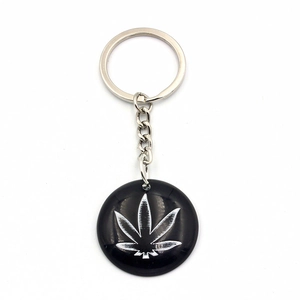 Black resin keychain featuring a silver maple leaf design on a circular pendant charm