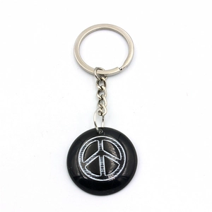 Close-up of black resin keychain featuring a white Peace sign with silver ring
