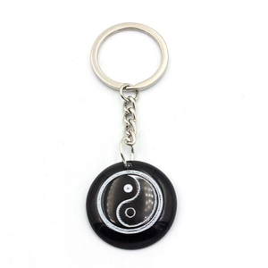 Detail view of a round resin keychain featuring a black and white Yin Yang symbol pattern