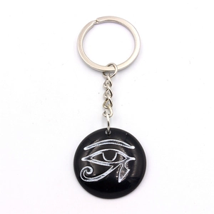 Detailed view of resin keychain featuring a white Eye of Horus logo on a black pendant