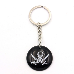 Detail of round black resin keychain with white pirate skull and crossbones emblem