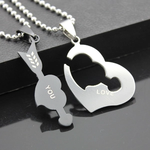 Close-up of interlocking heart and arrow pendants in black and silver with LOVE YOU engraving