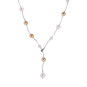 Détail d'un long collier en Y avec perles blanches et perles dorées sur chaîne argentée